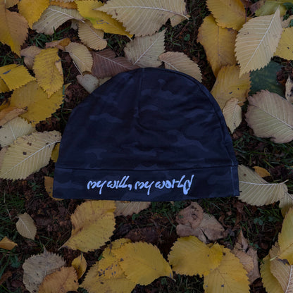 Navy blue beanie with 'my will, my world' text on a bed of autumn leaves
